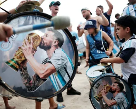Drums decorated with an image of Lionel Messi kissing a trophy are played at a beach gathering