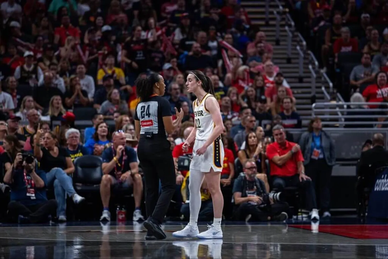 Indiana Fever guard Caitlin Clark argues with referee Gerda Gatling during a break in play.