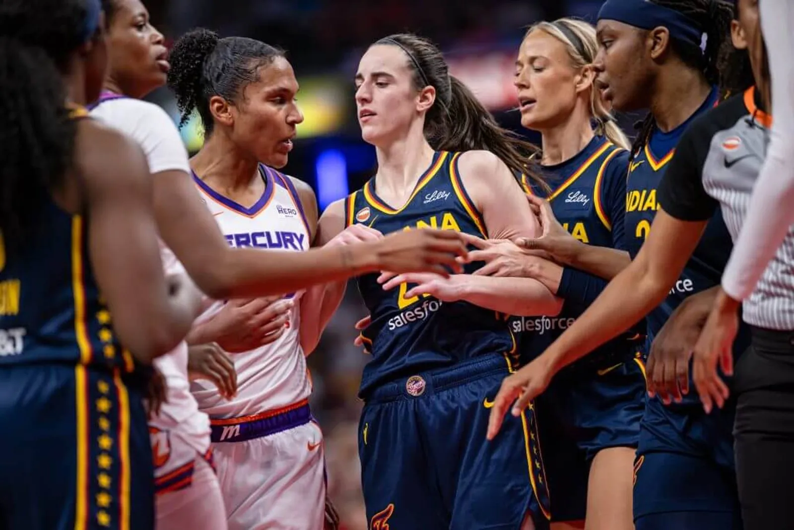 Mercury forward Alyssa Thomas, left, and Fever guard Caitlin Clark, center, get into a scuffle during the game at Gainbridge Fieldhouse as they're surrounded by teammates.